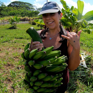 Person holding a bunch of bananas and flashing shaka